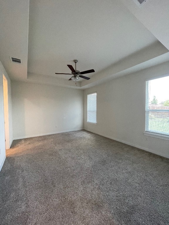 unfurnished room featuring ceiling fan, carpet floors, a raised ceiling, and a textured ceiling