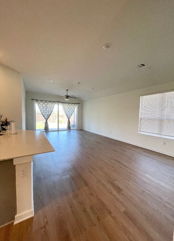 unfurnished living room with dark wood-type flooring and ceiling fan