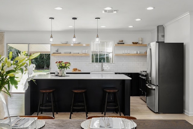 kitchen with tasteful backsplash, appliances with stainless steel finishes, a breakfast bar, ornamental molding, and pendant lighting