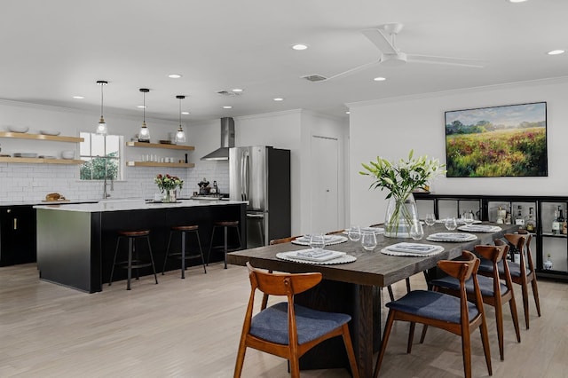 dining area with sink, ceiling fan, crown molding, and light hardwood / wood-style flooring