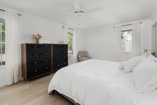 bedroom featuring light hardwood / wood-style flooring, crown molding, and ceiling fan