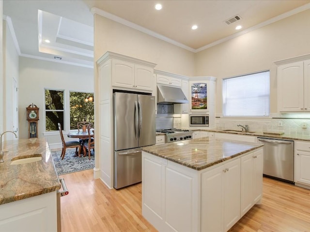 kitchen featuring a center island, stainless steel appliances, light stone counters, and white cabinetry