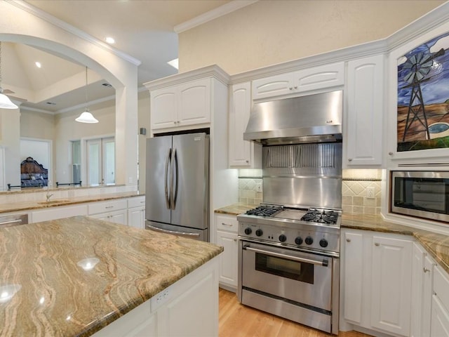 kitchen with light stone countertops, appliances with stainless steel finishes, backsplash, exhaust hood, and white cabinets