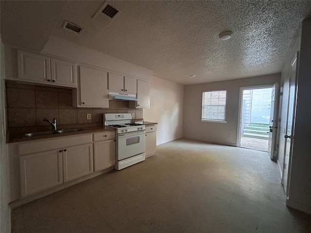 kitchen with a textured ceiling, tasteful backsplash, gas range gas stove, sink, and white cabinetry