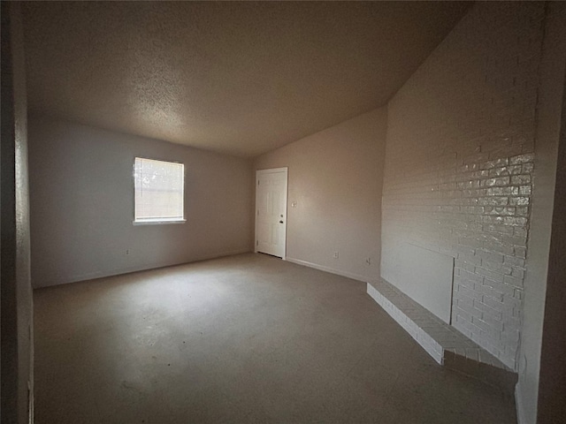 spare room with a textured ceiling, vaulted ceiling, and carpet floors