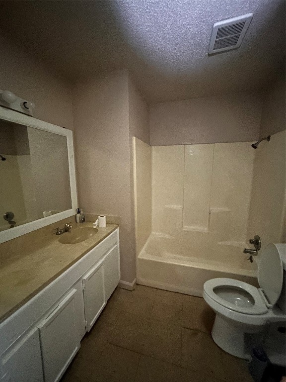 full bathroom with a textured ceiling, tile patterned floors, washtub / shower combination, vanity, and toilet