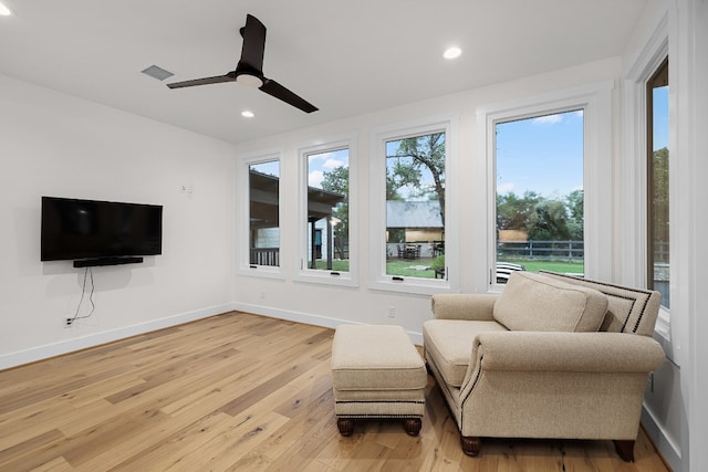 living area with a wealth of natural light, light hardwood / wood-style floors, and ceiling fan