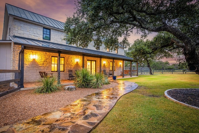 back house at dusk featuring a yard