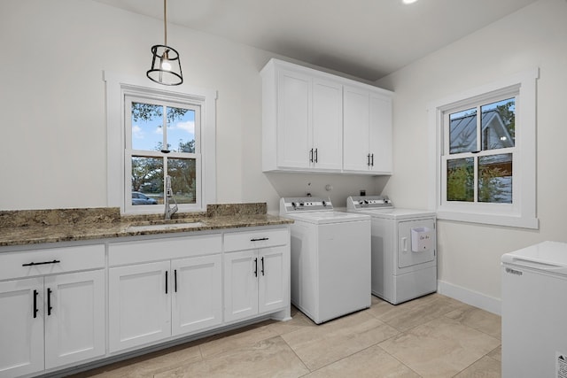 washroom with cabinets, washer and clothes dryer, and sink