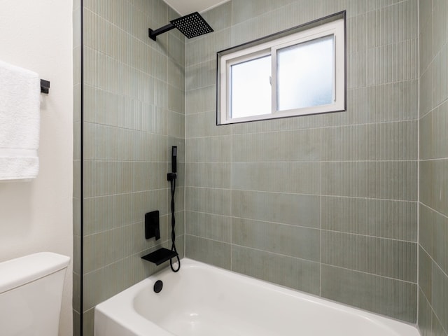 bathroom with tiled shower / bath combo and toilet