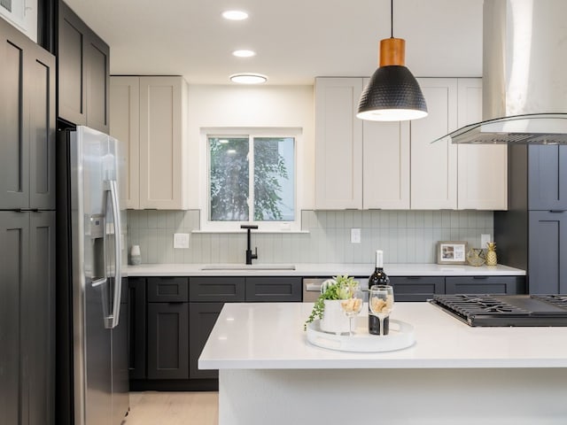 kitchen featuring sink, decorative light fixtures, decorative backsplash, island range hood, and appliances with stainless steel finishes