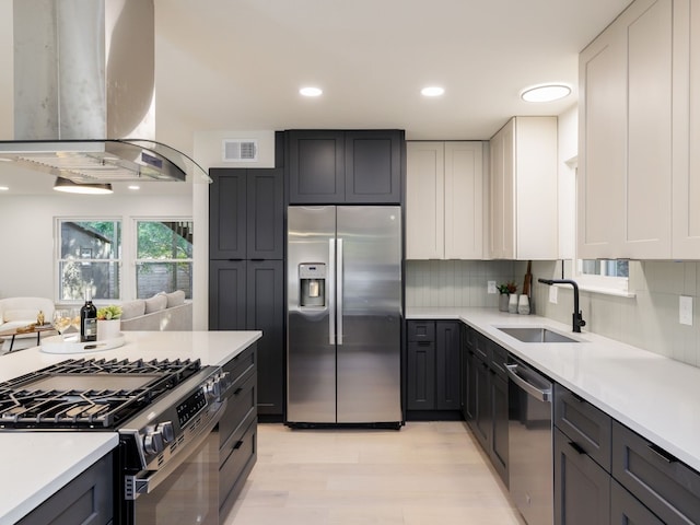 kitchen with decorative backsplash, appliances with stainless steel finishes, island range hood, sink, and white cabinetry