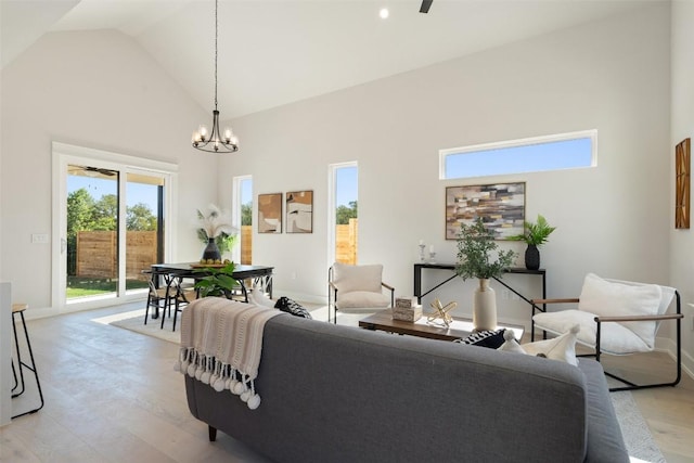 living room featuring ceiling fan with notable chandelier, light wood-type flooring, and high vaulted ceiling