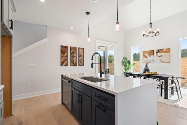 kitchen with stainless steel dishwasher, sink, hanging light fixtures, and light hardwood / wood-style flooring