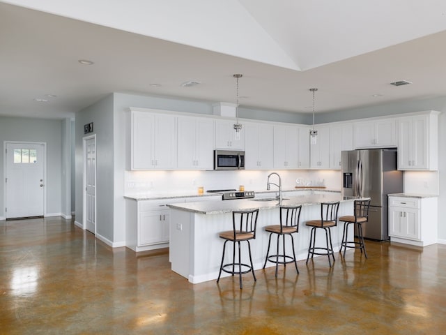 kitchen with hanging light fixtures, an island with sink, white cabinetry, and stainless steel appliances