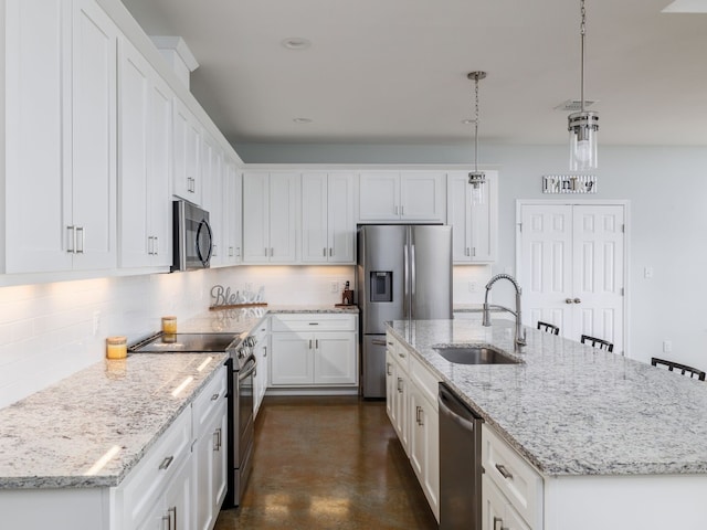 kitchen featuring white cabinets, a kitchen island with sink, appliances with stainless steel finishes, and hanging light fixtures