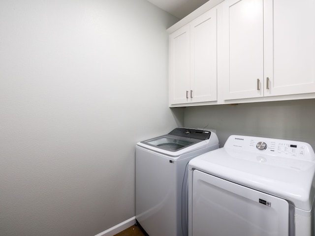 clothes washing area featuring washer and clothes dryer and cabinets