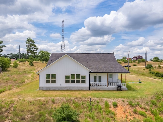 rear view of property featuring covered porch and a yard