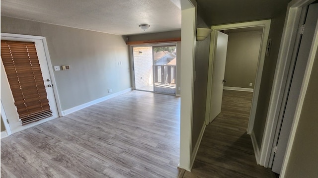 hallway with a textured ceiling and wood-type flooring