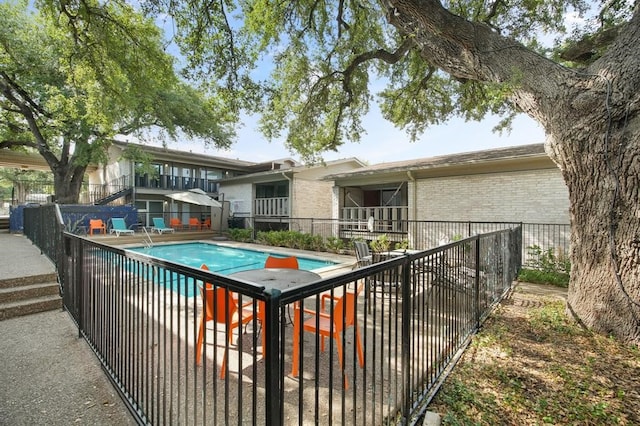 back of house with a fenced in pool and a patio