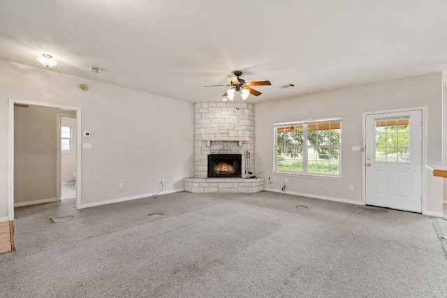 unfurnished living room with ceiling fan, carpet floors, and a stone fireplace