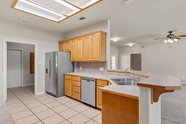 kitchen with sink, kitchen peninsula, a kitchen bar, appliances with stainless steel finishes, and ceiling fan