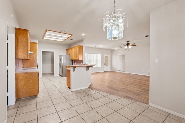 kitchen featuring a breakfast bar, light tile patterned floors, stainless steel fridge, and kitchen peninsula