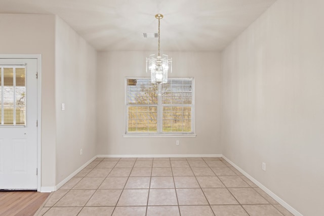 unfurnished dining area featuring light tile patterned floors and a notable chandelier