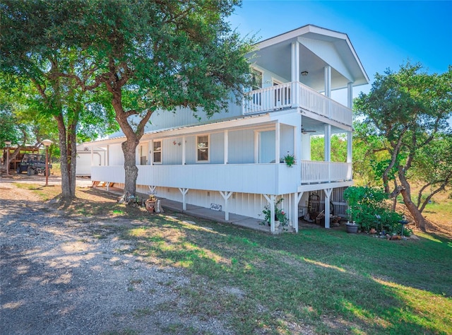 back of house featuring a balcony and a yard