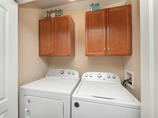 clothes washing area with washing machine and clothes dryer and cabinets