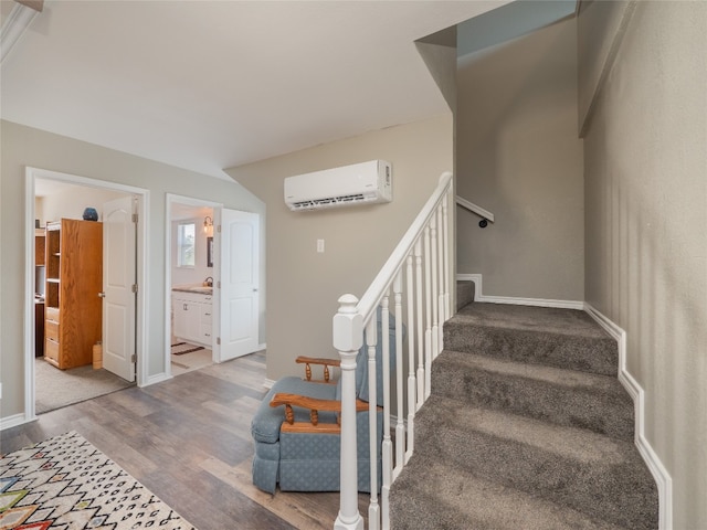 staircase featuring an AC wall unit and wood-type flooring