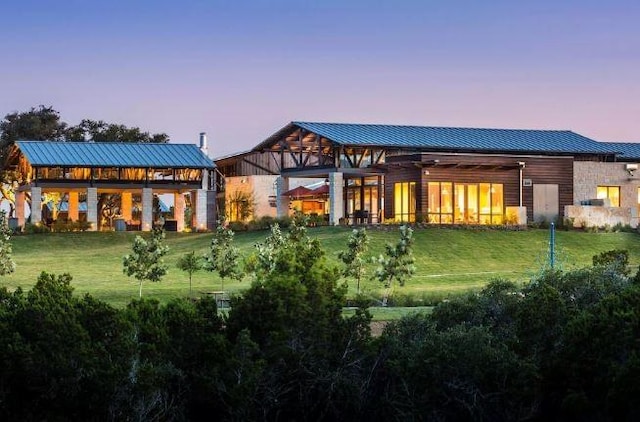 rear view of house with a standing seam roof, a lawn, and metal roof