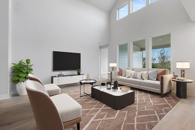 living area featuring high vaulted ceiling, baseboards, and wood finished floors