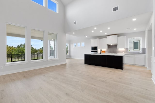 kitchen with light wood-style flooring, visible vents, open floor plan, and decorative backsplash