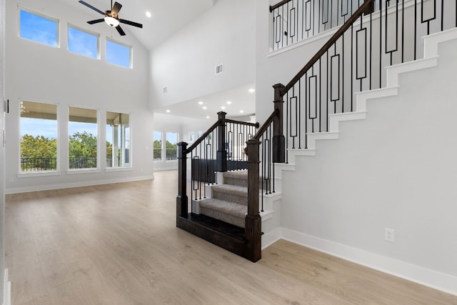 staircase featuring plenty of natural light, wood finished floors, visible vents, and baseboards