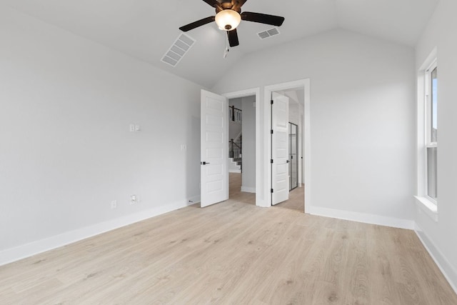 unfurnished bedroom with lofted ceiling, light wood-style flooring, visible vents, and baseboards