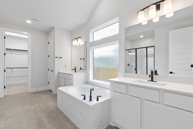 full bathroom with two vanities, a sink, a shower stall, a bath, and a walk in closet