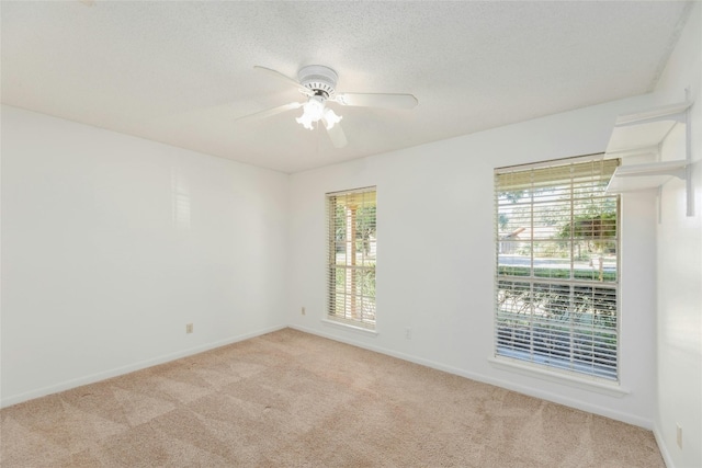 carpeted spare room featuring a textured ceiling, plenty of natural light, and ceiling fan