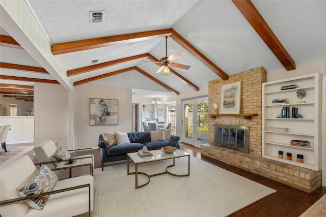 living room with a brick fireplace, ceiling fan with notable chandelier, a textured ceiling, vaulted ceiling with beams, and dark hardwood / wood-style floors