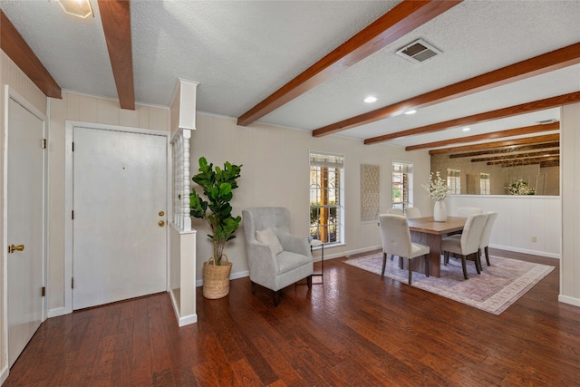 interior space featuring beam ceiling, dark hardwood / wood-style flooring, and a textured ceiling