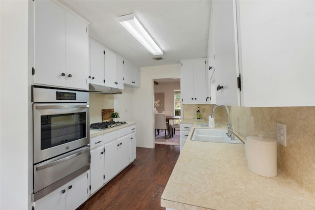 kitchen featuring decorative backsplash, stainless steel appliances, dark wood-type flooring, sink, and white cabinetry