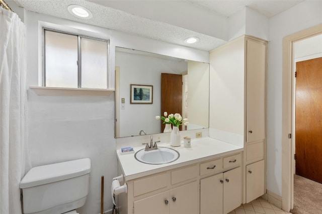 bathroom featuring a textured ceiling, vanity, and toilet