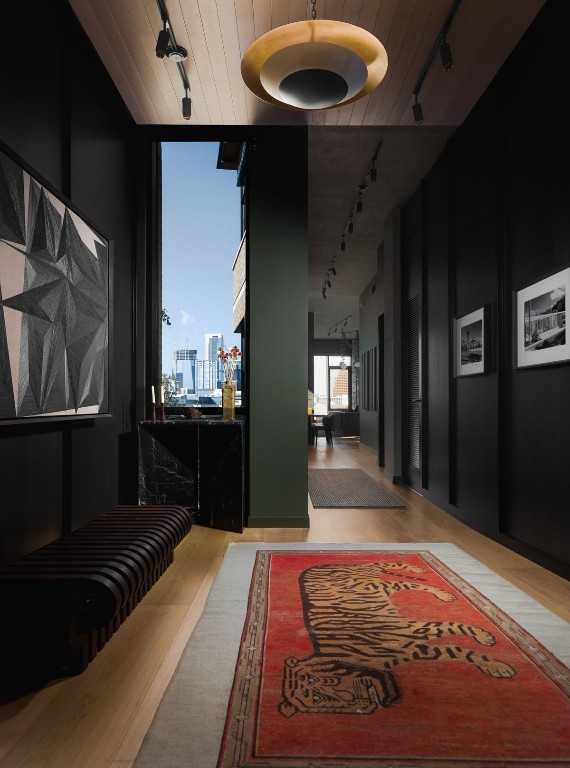 hallway with light hardwood / wood-style floors, wood ceiling, and track lighting