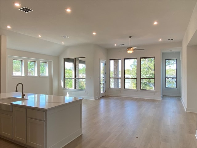 kitchen with ceiling fan, sink, an island with sink, and light hardwood / wood-style floors