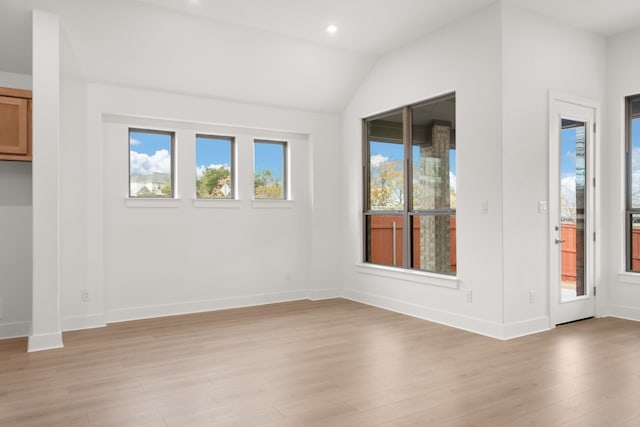 spare room with light wood-type flooring and vaulted ceiling