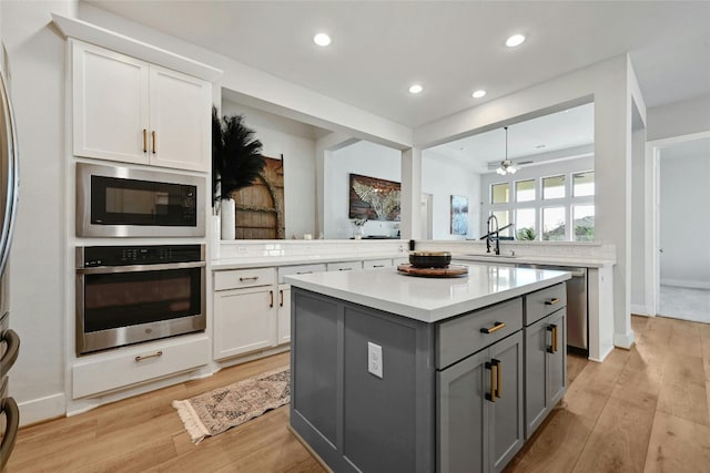 kitchen with white cabinetry, gray cabinets, stainless steel appliances, a center island, and ceiling fan