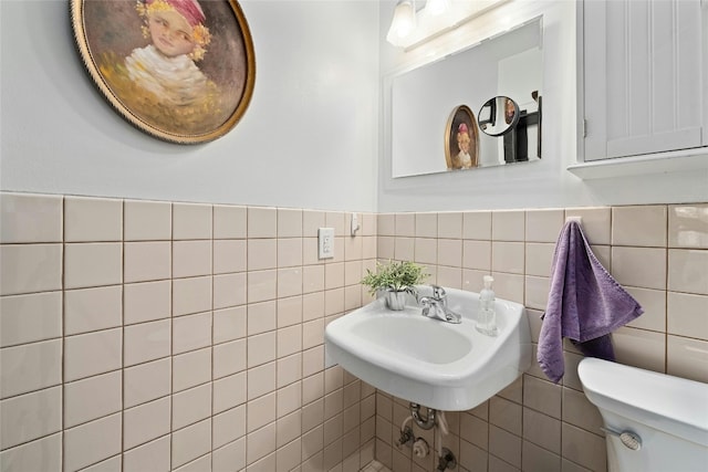 bathroom featuring tile walls, toilet, and sink