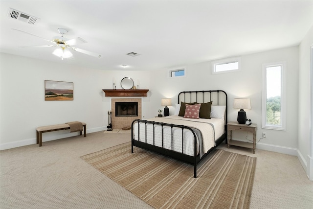 carpeted bedroom with multiple windows, a fireplace, and ceiling fan