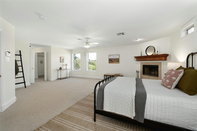 bedroom with light colored carpet, a fireplace, and ceiling fan