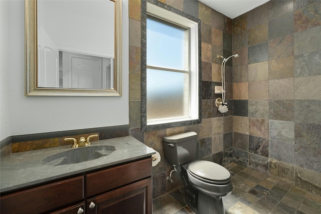 bathroom with vanity, toilet, tile walls, and a tile shower